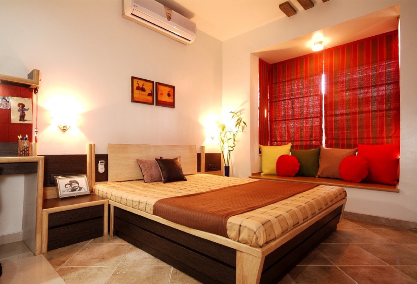 A bedroom with a red window seat, timber bed and study desk